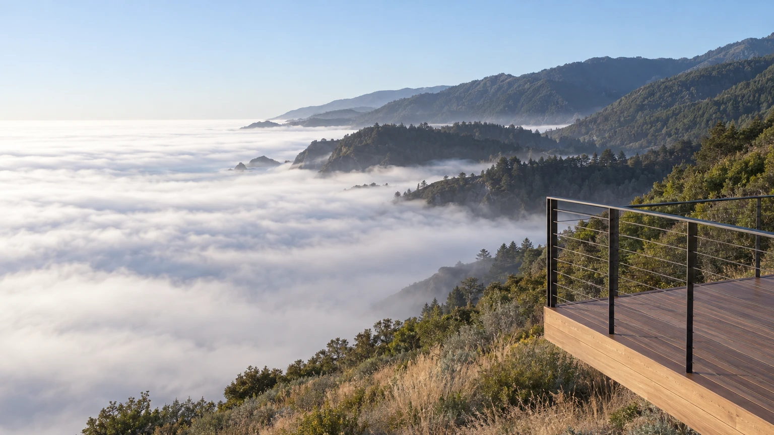 AI-generated Concept view from the end of an ipe deck with a slim steel railing over a sea of white fog, forested ridges and headlands rising beyond.