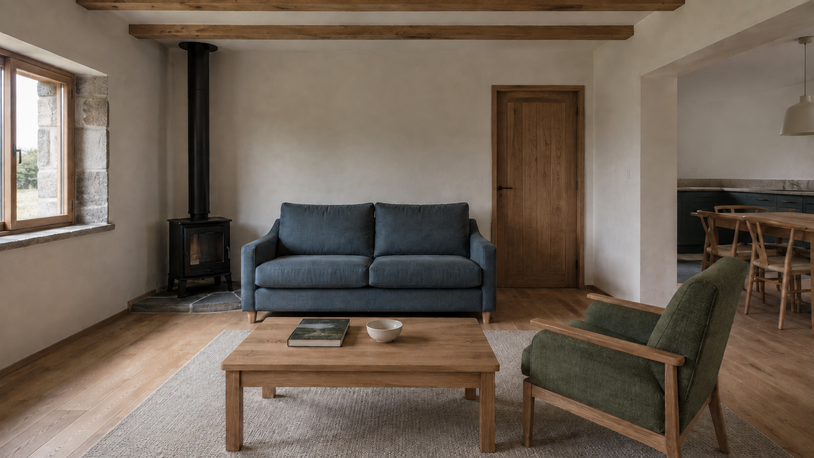 Blue sofa and green timber armchair around an oak table, with a kitchen glimpse beyond.