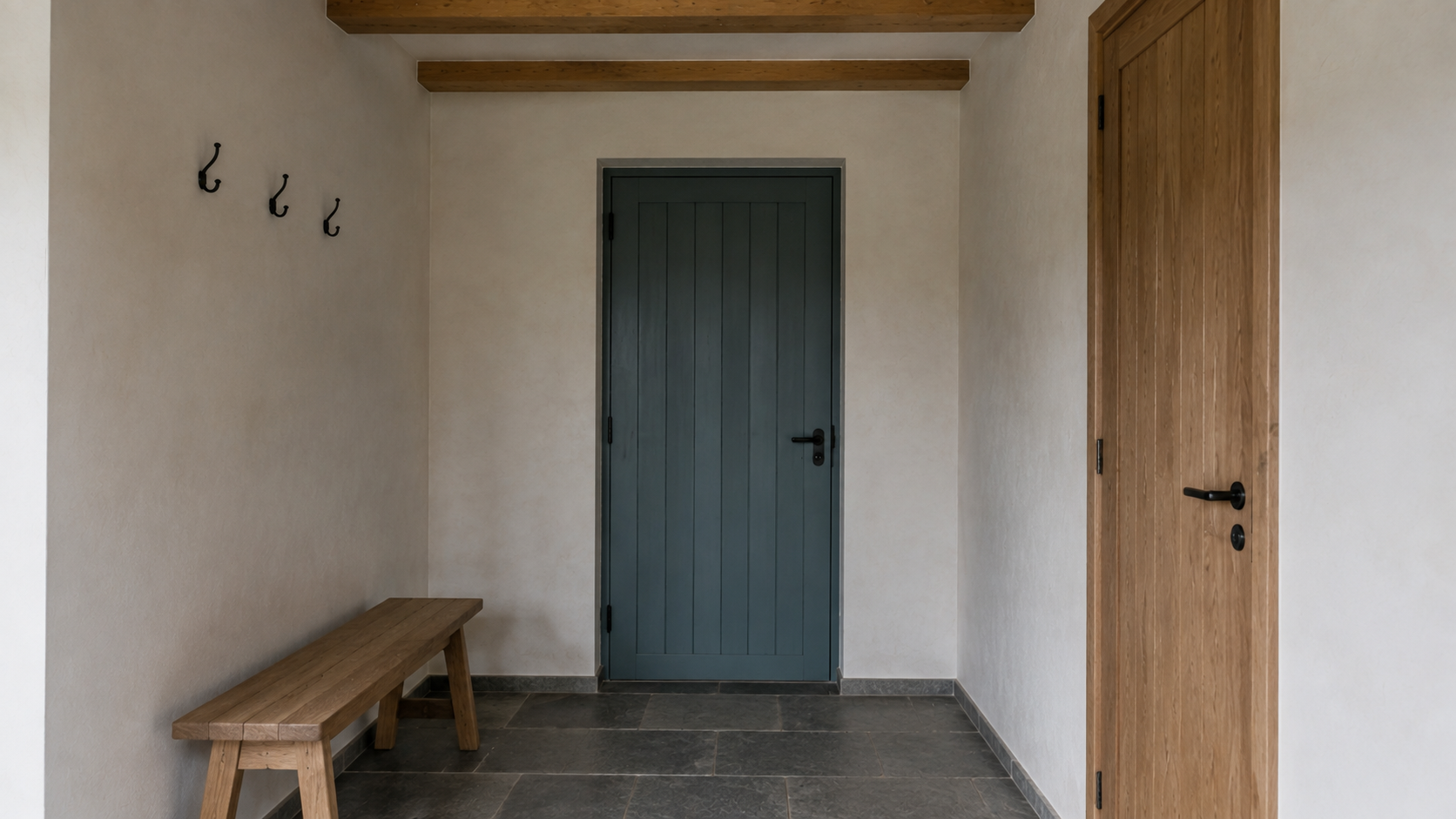 Inside the entry, a blue-green door faces a short bench and three wall hooks.