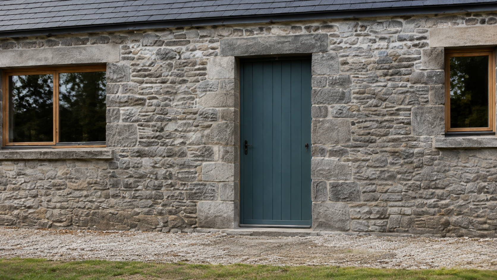 Close arrival view of the blue-green front door and neighbouring timber windows.