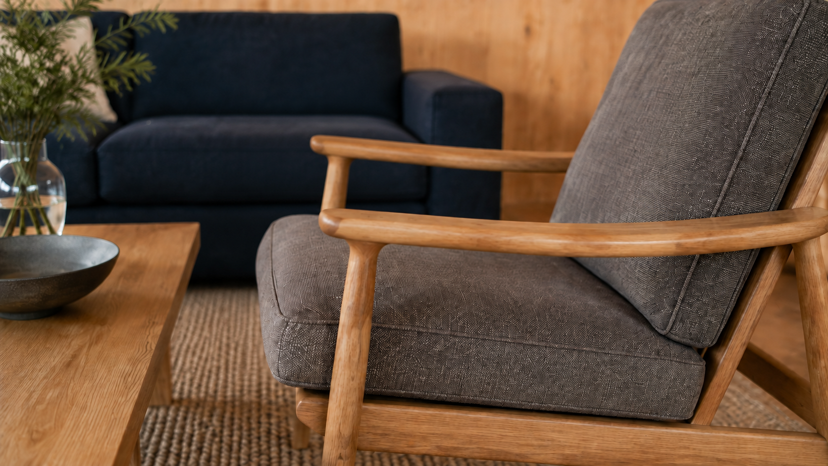 Textured grey upholstery, an ash arm and the navy sofa bring the living room’s material palette close. AI-generated Concept.