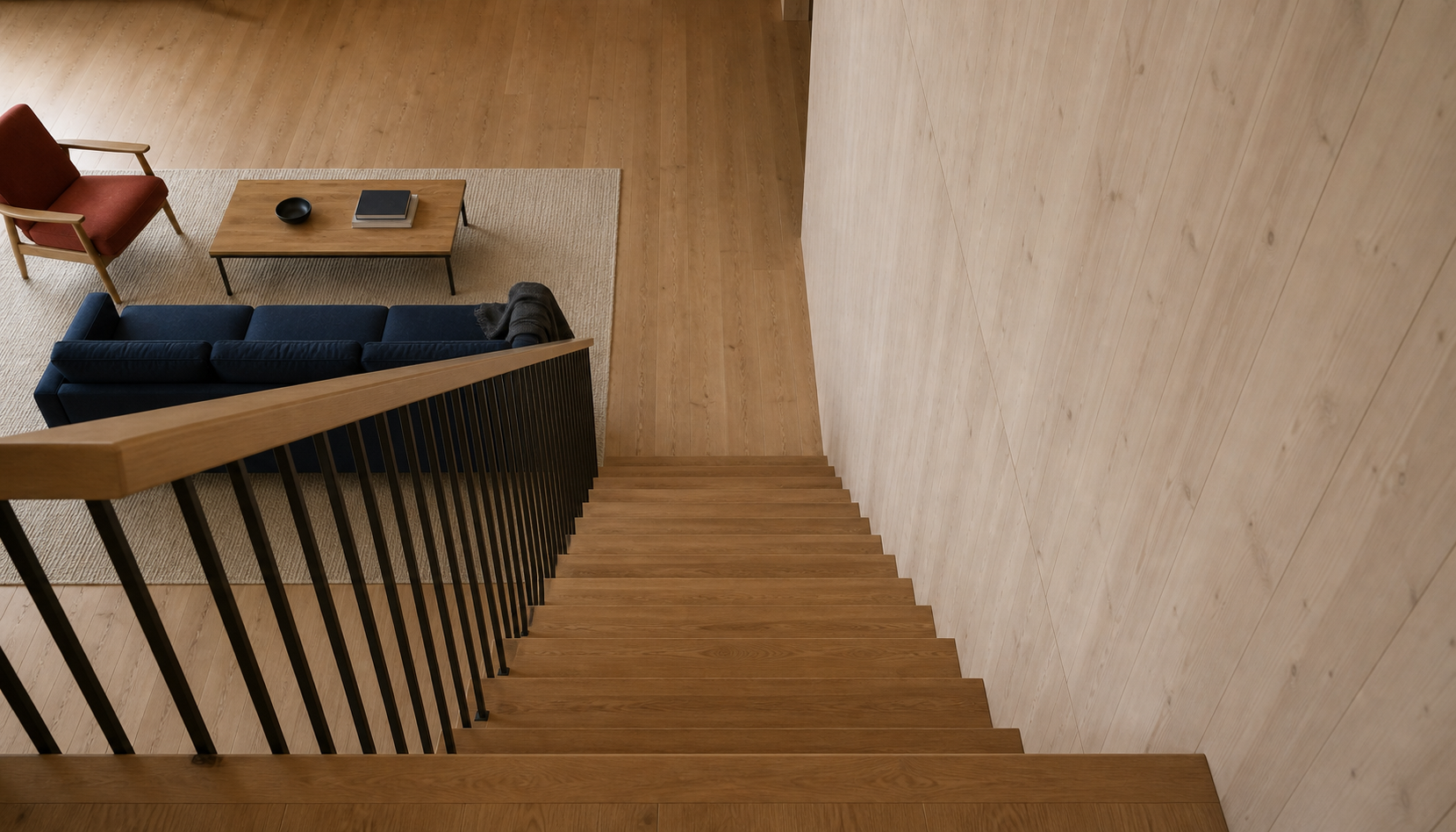 View down the single stair, with wall to the right and dark inner guard to the left, towards the sofa below.